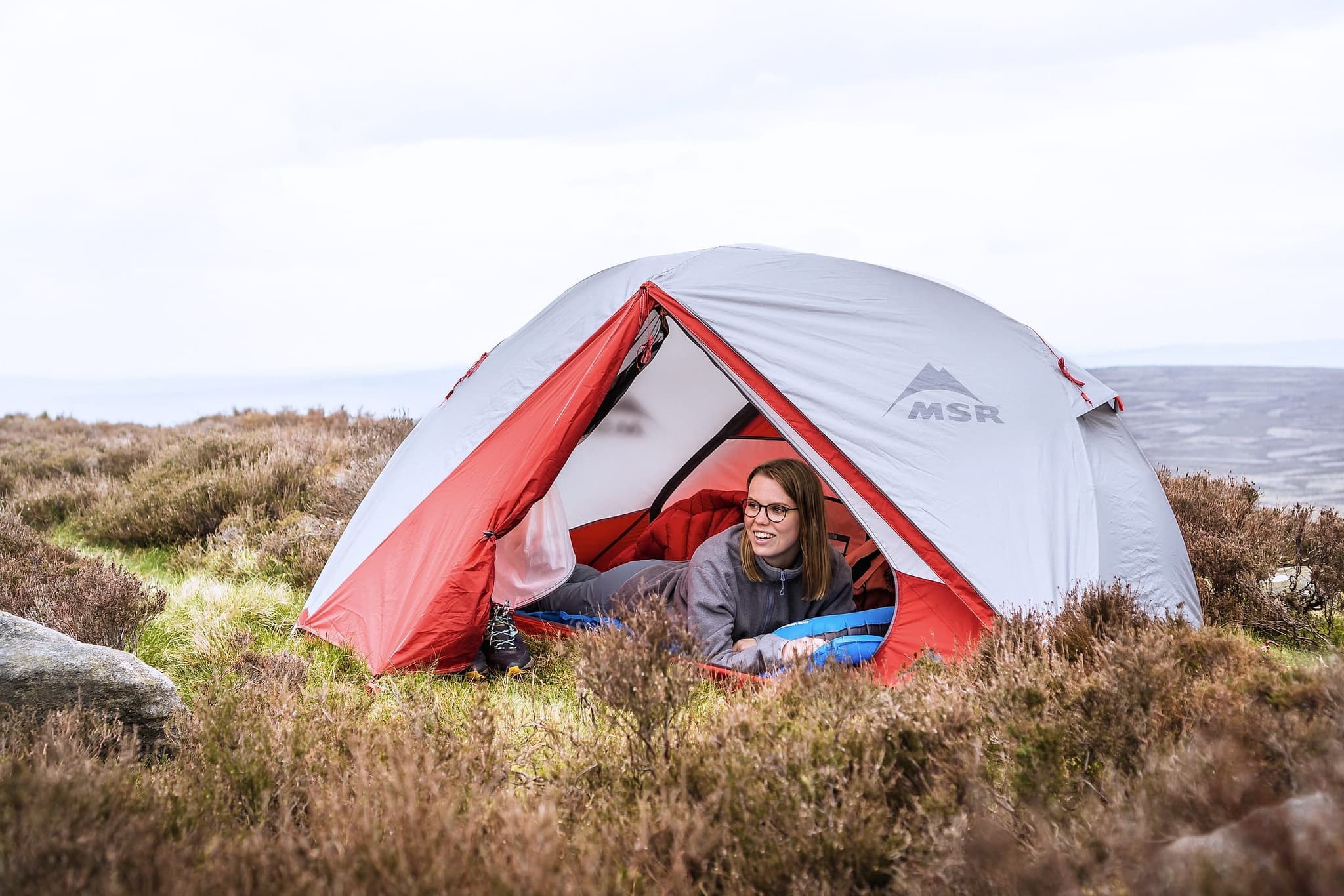 A tent pitched on cold heather moorland with a camping mat visible in the porch