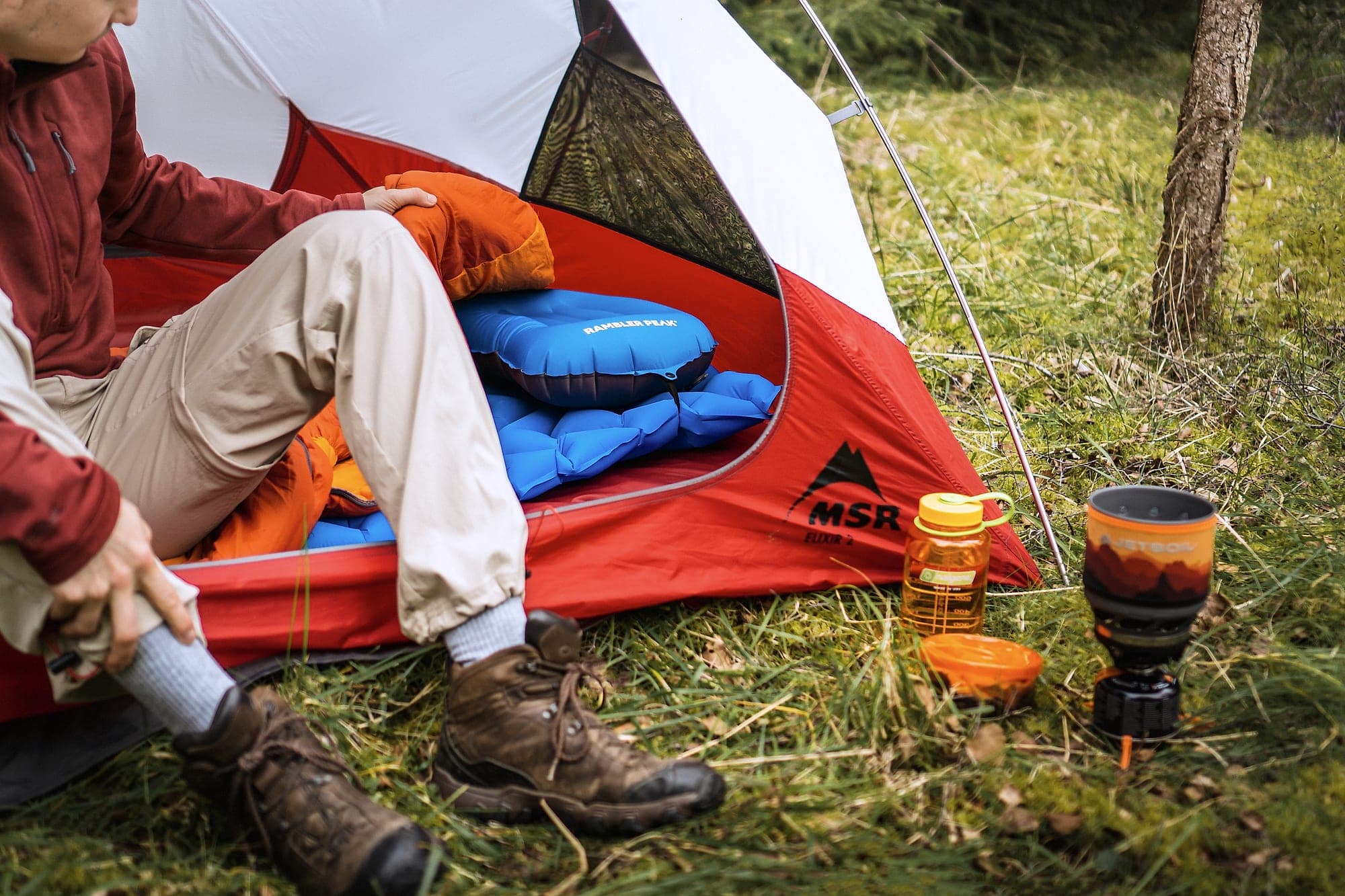 The complete Rambler Peak sleep system set up in a tent porch with mat, pillow and stove